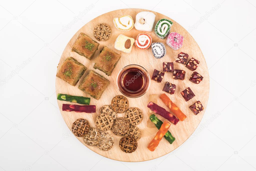 top view of wooden board with delicious turkish sweets and tea isolated on white