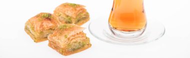 Beyaz panoramik kareye izole edilmiş Türk baklavası yakınında bir fincan çay.