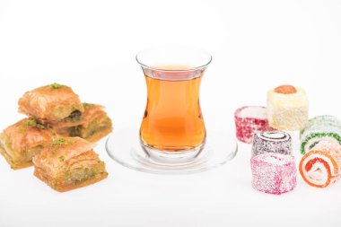 Baklava yakınlarında bir fincan çay, beyaz üzerine izole edilmiş Türk lokumu.
