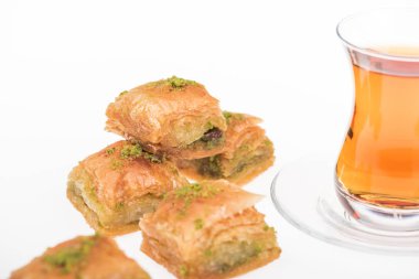 Beyaz üzerine izole edilmiş baklava yakınlarındaki çay fincanının yakın görüntüsü