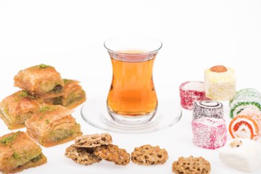Baklava yakınlarında bir fincan çay, Türk lokumu ve beyaz tenli gozinaki.