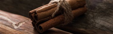 close up view of cinnamon sticks on wooden background, panoramic shot clipart