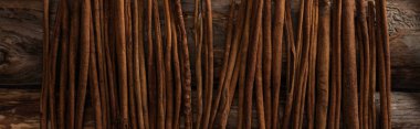 top view of cinnamon sticks on wooden background, panoramic shot clipart