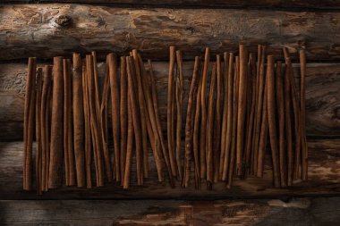 top view of cinnamon sticks on wooden background clipart