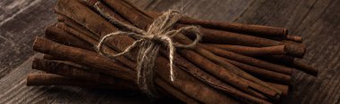 cinnamon sticks in bunch on wooden rustic table, panoramic shot clipart