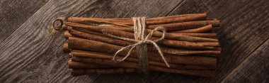 top view of cinnamon sticks in bunch on wooden rustic table, panoramic shot clipart
