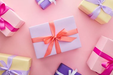 Pembe arka planda kurdeleli ve fiyonklu renkli hediye kutularının üst görünümü