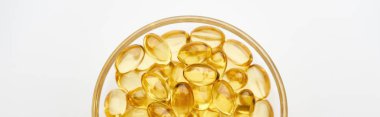 top view of golden fish oil capsules in glass bowl on white background, panoramic shot clipart