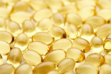 close up view of golden fish oil capsules clipart