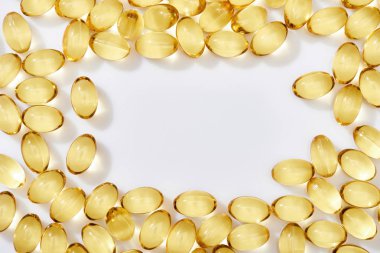 top view of golden fish oil capsules arranged in frame on white background clipart