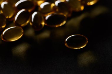 Koyu arkaplanda altın balık yağı kapsüllerinin yakın görüntüsü