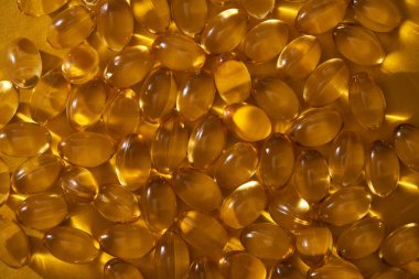 top view of golden shiny fish oil capsules in dark clipart