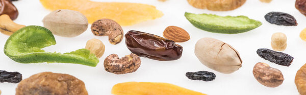 close up view of tasty assorted nuts, dried fruits and candied fruit isolated on white, panoramic shot