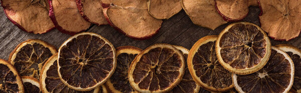 panoramic shot of dried orange and apple slices on wooden background