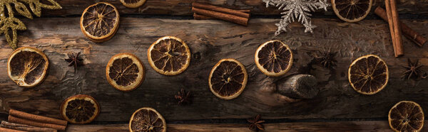 top view of dried citrus slices with anise, cinnamon sticks and decorative snowflakes on wooden background, panoramic shot