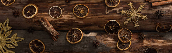 top view of dried citrus slices with anise, cinnamon sticks and decorative snowflakes on wooden background, panoramic shot