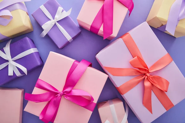 紫色の背景に弓のあるカラフルなプレゼントのトップビュー — ストック写真
