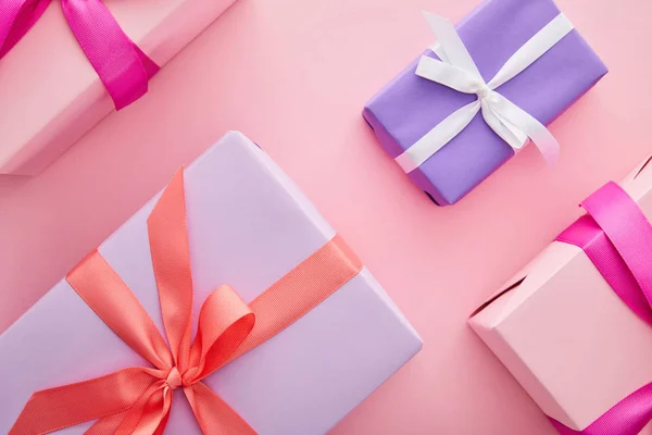 平铺着五彩缤纷的礼品盒 彩带和蝴蝶结散落在粉色的背景上 — 图库照片