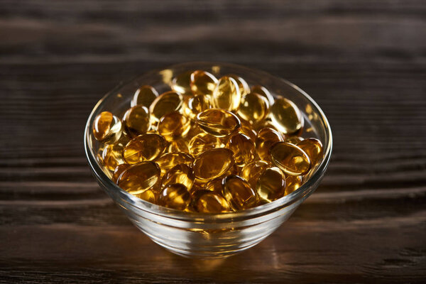 golden fish oil capsules scattered on wooden table