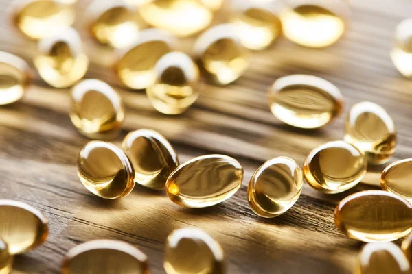 Close Zicht Gouden Visolie Capsules Verspreid Houten Tafel — Stockfoto