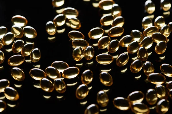 Shiny Golden Fish Oil Capsules Scattered Black Background — Stock Photo, Image