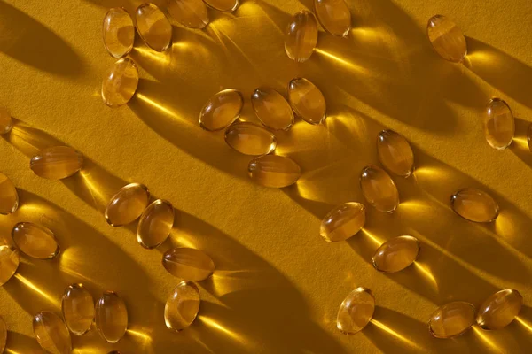 Golden Shiny Fish Oil Capsules Scattered Yellow Background Dark — Stock Photo, Image