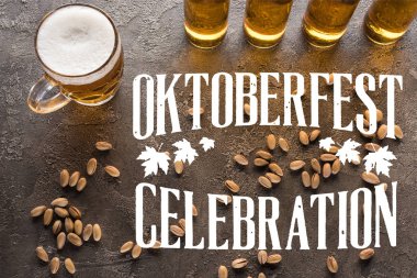 Gri yüzeyde, şam fıstığı yakınında şişe ve bir bardak light bira. Oktoberfest kutlama harfleriyle.