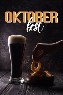 Tabağın yanında bir şişe bira ve ahşap masada abur cubur ve Oktoberfest harfleriyle birlikte.