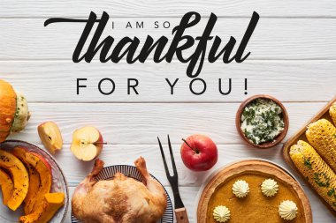 top view of roasted turkey, pumpkin pie and grilled corn served on white wooden table with i am so thankful for you illustration clipart