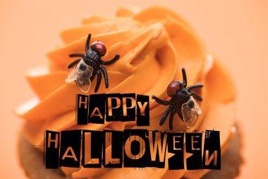 close up view of spooky Halloween cupcake with flies and happy Halloween illustration on cream isolated on orange clipart