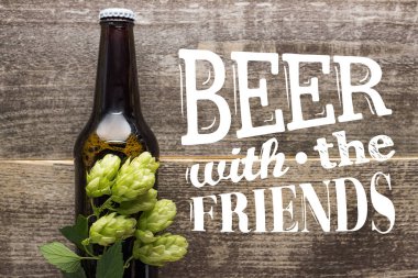 Şişedeki taze biranın en üst görüntüsü yeşil zıpla ahşap yüzey üzerinde bira ve arkadaşlarla harf.