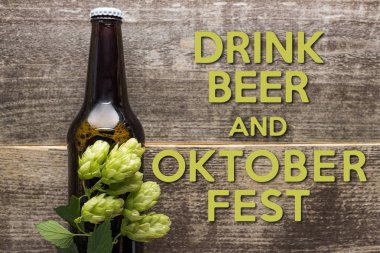 Şişe içindeki taze biranın en üst görüntüsü yeşil zıpla ahşap zıpla bira iç ve Oktoberfest harfleri yaz