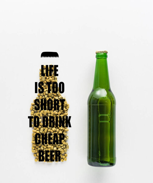 top view of bottle of beer near pressed hop with life is too short to drink cheap beer lettering isolated on white 