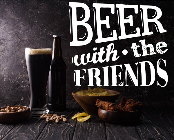 стекло и бутылка пива возле миски с закусками на темном деревянном столе с белым пивом с иллюстрацией друзей
