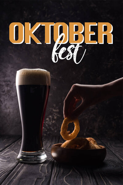 бутылка и стакан пива возле тарелки с закусками на деревянном столе с надписью Октоберфест

