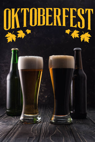 glasses of fresh light and dark beer near bottles on wooden table with yellow Oktoberfest lettering