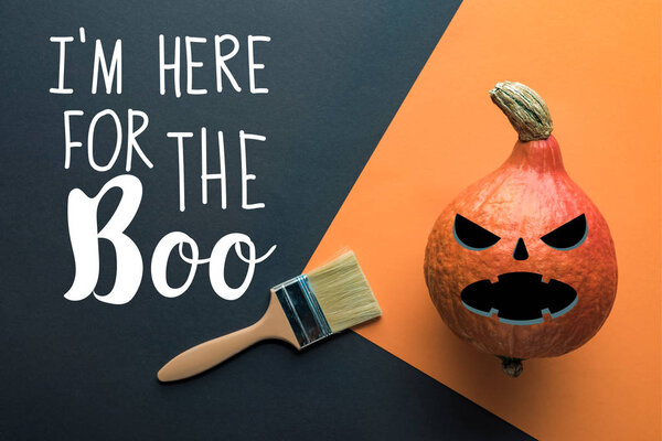 top view of Halloween pumpkin near paintbrush on black and orange background with i am here for the boo illustration