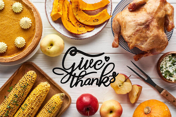 top view of roasted turkey, pumpkin pie and grilled vegetables served on white wooden table