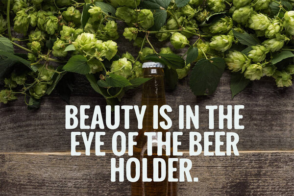 top view of fresh beer in bottle with green hop on wooden surface with beauty is in the eye of the beer holder illustration