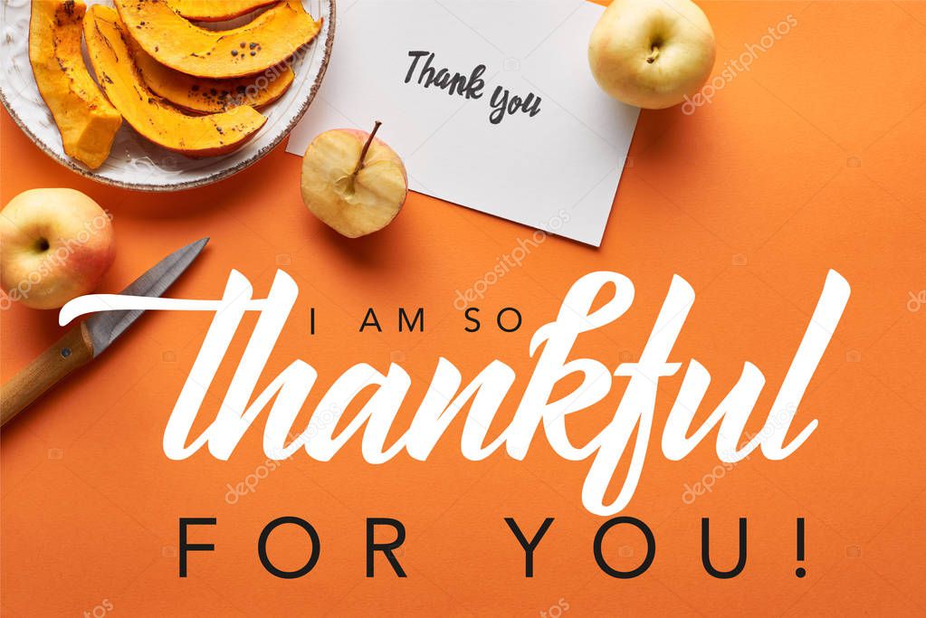 top view of pumpkin, apples, knife and thank you card on orange background with i am so thankful for you illustration