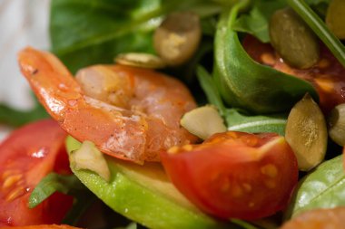 Balkabağı çekirdekli taze yeşil salata, kiraz domatesleri, karidesler ve avokado yakın plan.