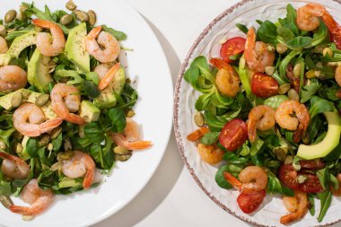 Tabakta karides ve avokado olan taze yeşil salata manzarası.