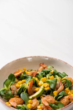 Beyaz arka planda taze yeşil salata, karides ve avokado.