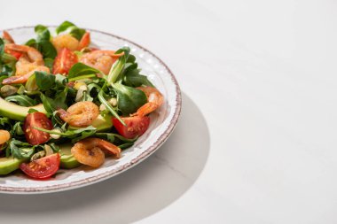 Taze yeşil salata, beyaz arka planda karides ve avokado.