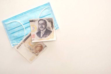KYIV, UKRAINE - 25 Mart 2020: Tıbbi maskenin üst görüntüsü ve beyaz arka planda yırtılmış banknot