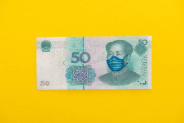 Sarı zemin üzerine tıbbi maske çizilmiş banknotun üst görüntüsü