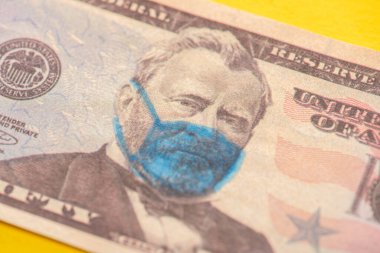 Sarı arka planda tıbbi maske çizilmiş dolar banknotunun görüntüsünü kapat