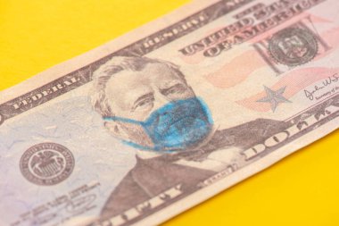 Sarı arka planda tıbbi maske çizilmiş dolar banknotunun görüntüsünü kapat