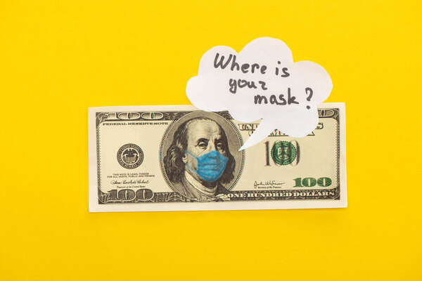 КИЕВ, УКРАИНА - 25 МАРТА 2020 г.: вид сверху на банкноту доллара с нарисованной медицинской маской и речевым пузырем на желтом фоне
