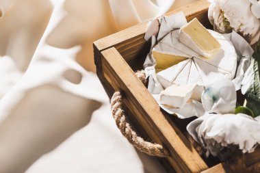 Camembert 'le Fransız kahvaltısını ahşap tepside, desenli, şakayıklı beyaz kumaşla yakın çekim.